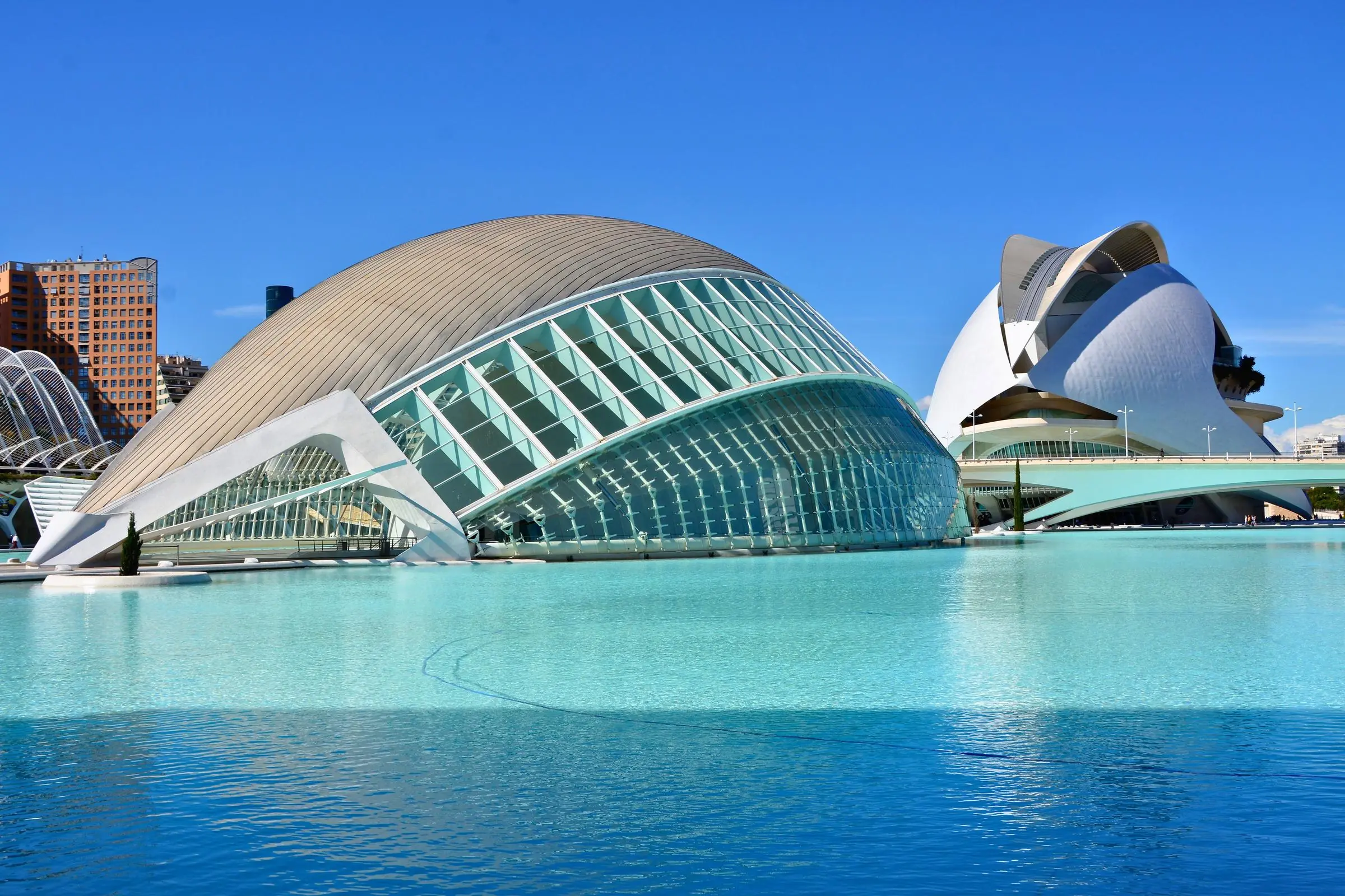 The exterior of the Hemisfèric building reflecting in the surrounding blue pools