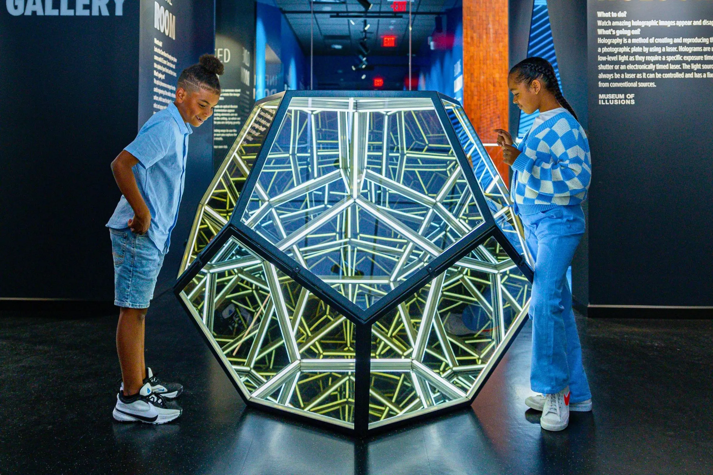 Museum of Illusions Valencia Two children observing an illuminated optical illusion in a darkened room