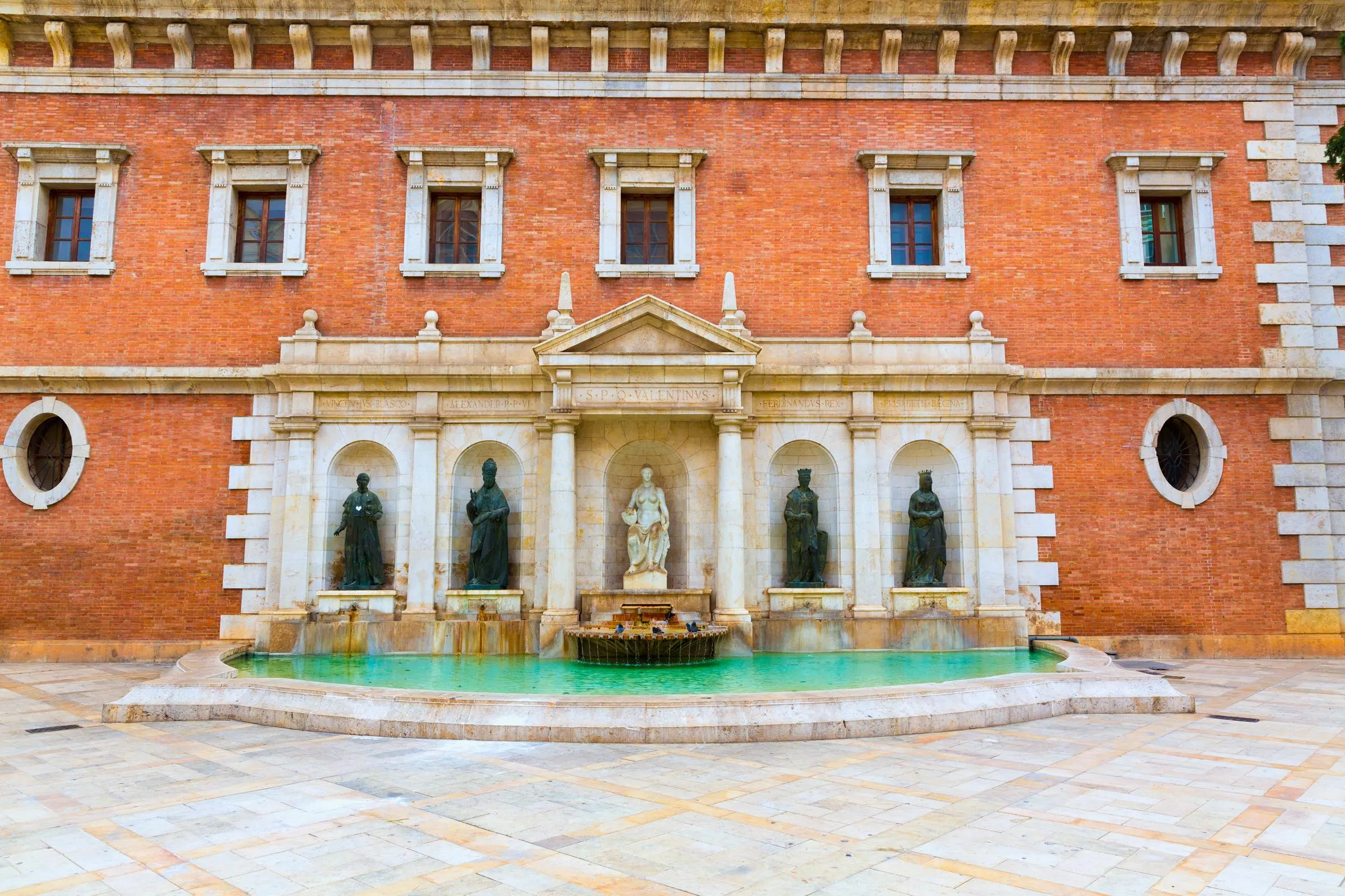 The classical fountain and statues adorning the brick facade at Plaza del Patriarca